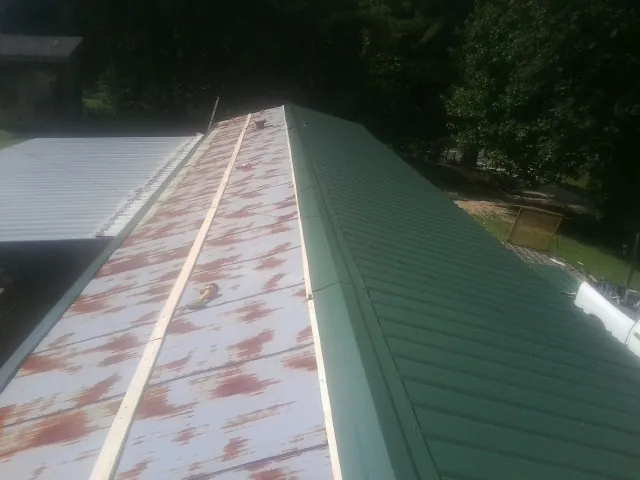 Old rusted panels beside newly installed green metal roofing — Wind Damage Roof Repair by Roofing Brothers in North Powder
