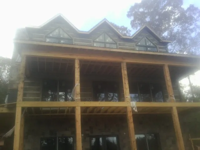 Dormers and porch framing on a large log home under construction — Roof Coating work by our crew in North Powder