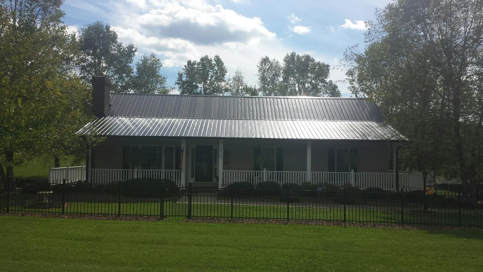 Gray metal roof on a brick ranch with a full width front porch — Gutter Guard Installation work by our crew in North Powder
