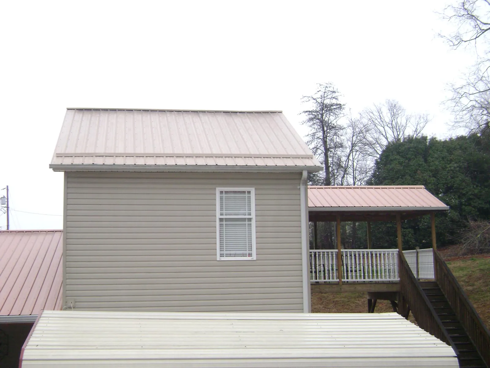 Tan metal roofs on a two story addition and attached porch, from a Roof Replacement job in North Powder