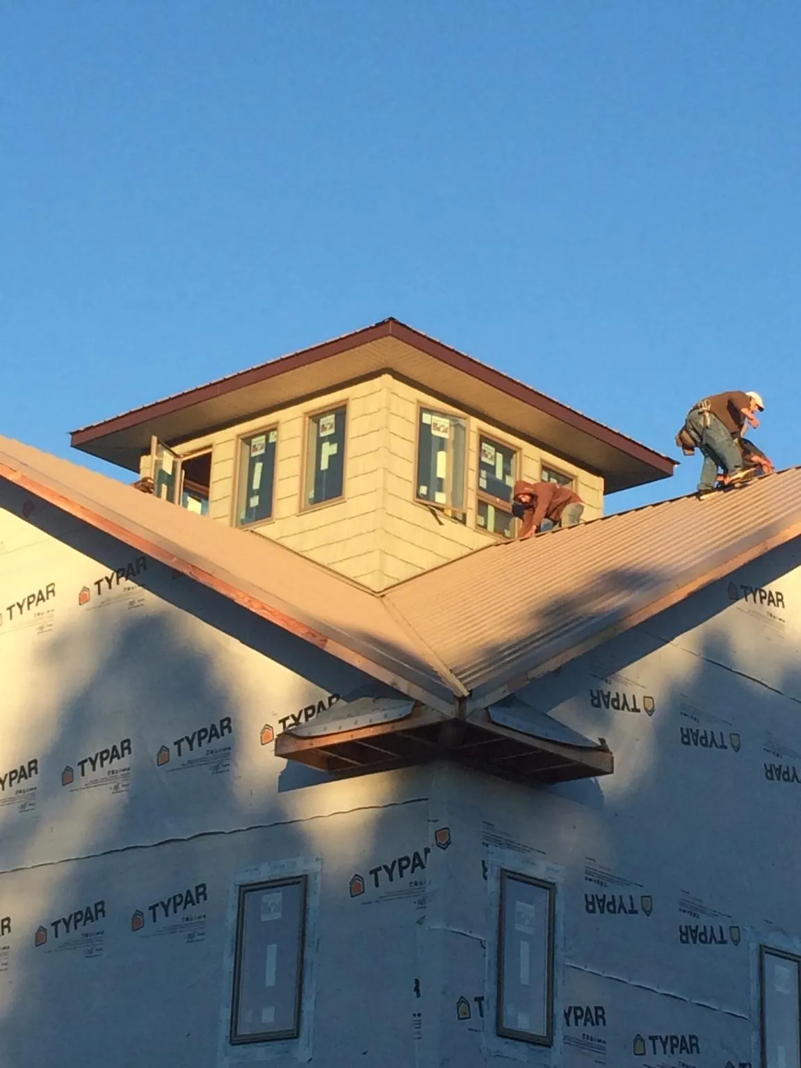 Roofers working around a rooftop cupola on a new metal roof at sunset — Roof Waterproofing in North Powder by Roofing Brothers